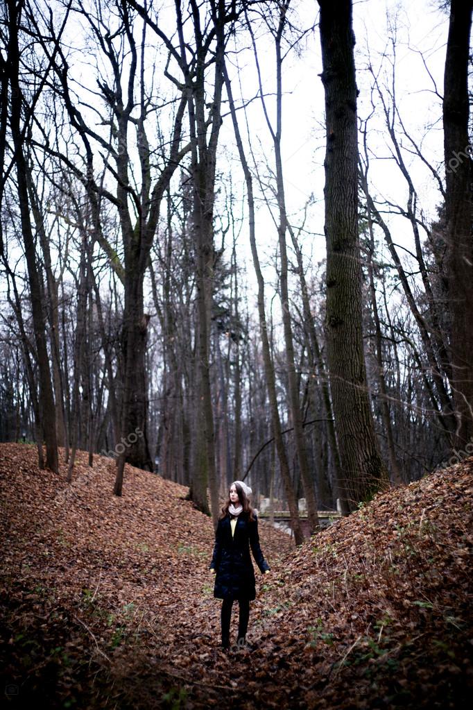 Woman standing in dark cold forest background