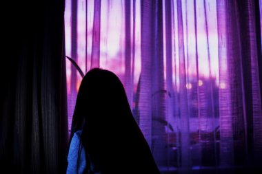 karanlık odada gün batımı penceresi arka planda kadın