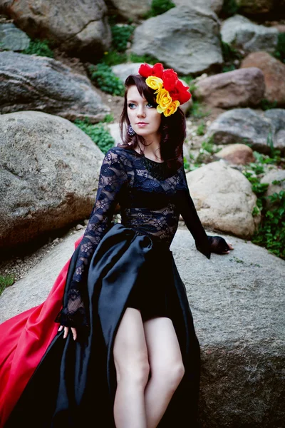 Mode portret van vrouw in zwarte en rode kant jurk en bloemen op steen buiten achtergrond — Stockfoto