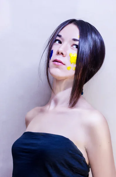 Schoonheid gezicht van een meisje geschilderd blauw en geel — Stockfoto