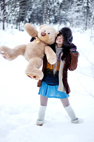 Mujer feliz en abrigo de piel y ushanka con oso sobre fondo blanco nieve invierno —  Fotos de Stock