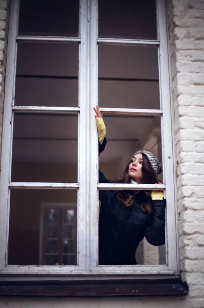 Beautiful woman looking through the window and fearing of something — Stock Photo, Image