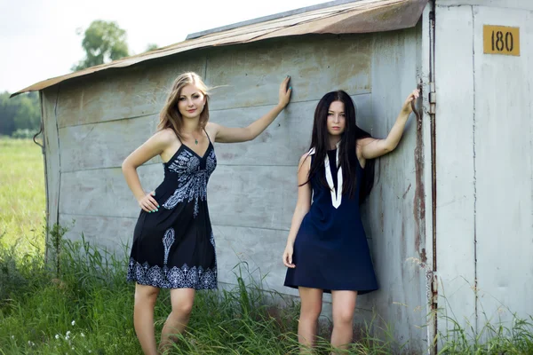 Two young women in dresses standing next to the garage — Stock Photo, Image