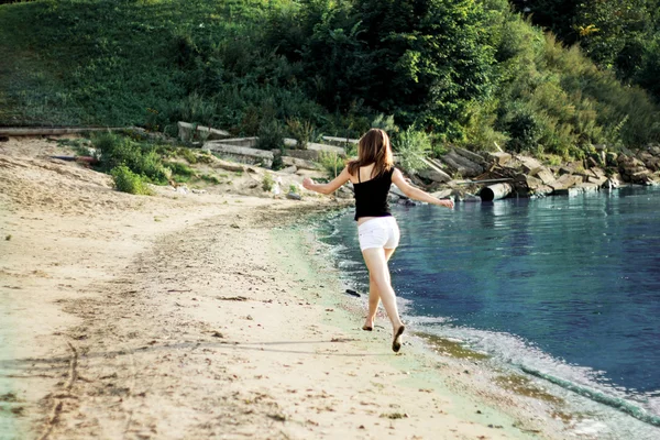 Szczęśliwa kobieta działa koryta skoki na plaży — Zdjęcie stockowe