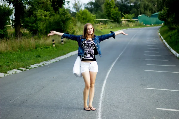 Mladá šťastná žena s pytlem na silnici — Stock fotografie