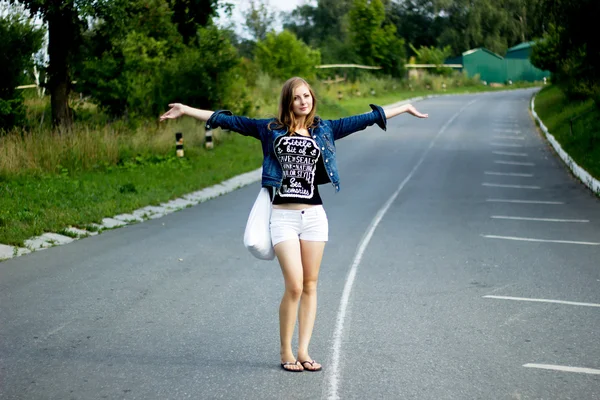 Jeune femme heureuse avec un sac sur une route — Photo