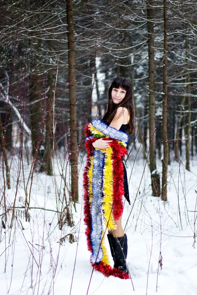 Schöne Frau mit hellem Lametta im Winterwald — Stockfoto