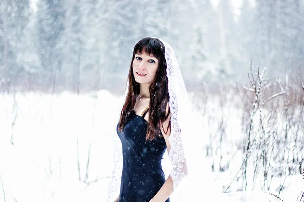 Όμορφη νύφη κάτω από πέπλο σε φόντο λευκό χιόνι — Φωτογραφία Αρχείου