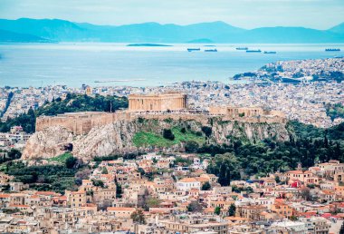 Lycabettus Tepesi 'nden Atina Akropolis manzarası. Filopappos Tepesi ve Saronik Körfezi, liman ve Pire kenti arka plandadır..