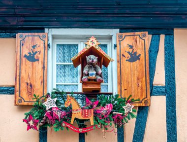 Ahşap panjurlu bir pencere ve Noel süslemeli bir oyuncak ayı. Ribeauville, Alsace, Fransa.