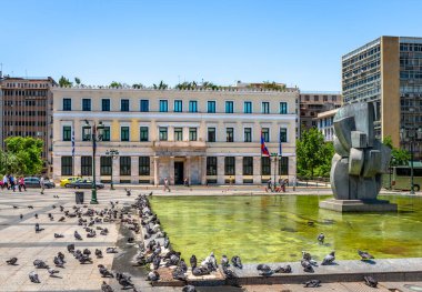 Atina, Yunanistan - 21 Mayıs 2022: Athinas Caddesi 'ndeki eski belediye binası, Kotzia Meydanı' nın karşısında, çeşmenin yanında bir sürü güvercin dinleniyor.