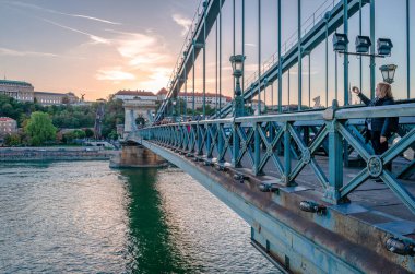 Budapeşte, Macaristan - 4 Ekim 2018: Zincir Köprüsü ile günbatımı ve şehrin batı yakası olan Buda ile arka plan. Tuna Nehri 'nin yansımaları.
