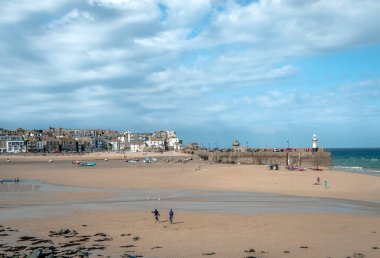 Panoramic view of the St Ives harbour, Cornwall, England, UK. Low tide, dramatic sky, unidentified people play at the beach.
