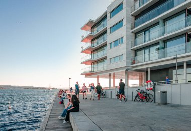 Oslo, Norway - August 13 2022: Incidental people enjoy the sunset on the waterfront of Tjuvholmen.