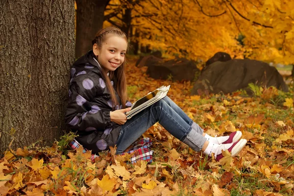 Smiling girl playing on the tablet in the park — Stock Photo, Image