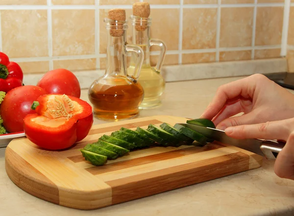 Fille coupe un concombre sur une planche à découper — Photo