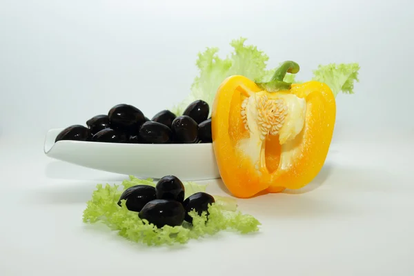 Olives in a bowl with lettuce and pepper — Stock Photo, Image