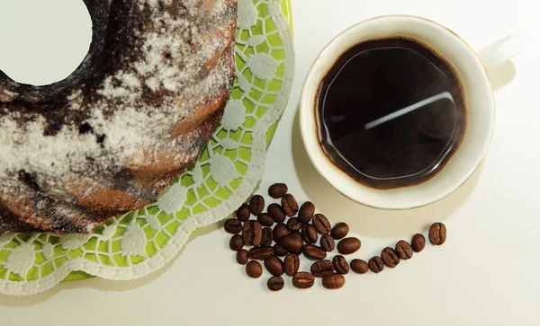 Bolo de chocolate, uma xícara de café e grãos de café — Fotografia de Stock