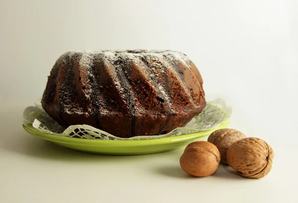 Chocolate cake on a plate and walnuts — Stock Photo, Image