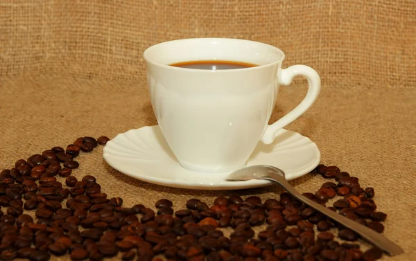 Bir fincan kahve, kahve çekirdekleri ve bir çay kaşığı — Stok fotoğraf