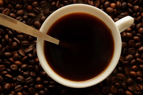 Bir fincan kahve, kahve çekirdeği ve bir çay kaşığı, üstten görünüm — Stok fotoğraf