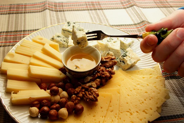 Un trozo de queso en un tenedor en la mano del hombre y corrió hacia abajo con su miel — Foto de Stock