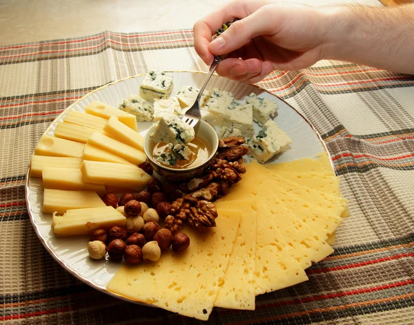 Un trozo de queso en un tenedor en la mano del hombre y corrió hacia abajo con su miel — Foto de Stock