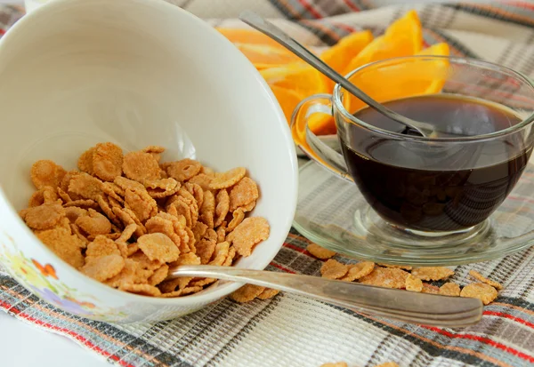 Flocos em um prato profundo, xícara de café e laranja, fatiado — Fotografia de Stock