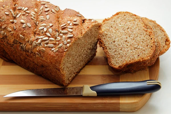 Cut into slices of bran bread, sprinkled with sunflower seeds — Stock Photo, Image