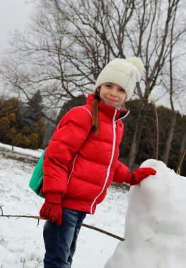 Kızın yüzünde bir gülümseme yapma bir kardan adam ve maliyeti