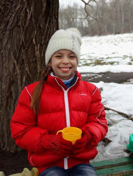 Pretty girl with a smile on her face holding a cup of tea on a winter outing — Stock Photo, Image