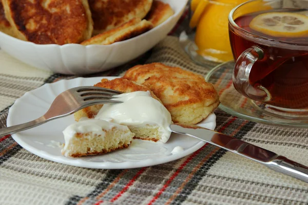 Frittelle con panna acida e una tazza di tè per colazione — Foto Stock