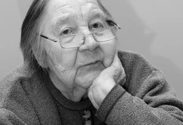 Abuela anciana sentada, apoyada en su brazo y pensando — Foto de Stock