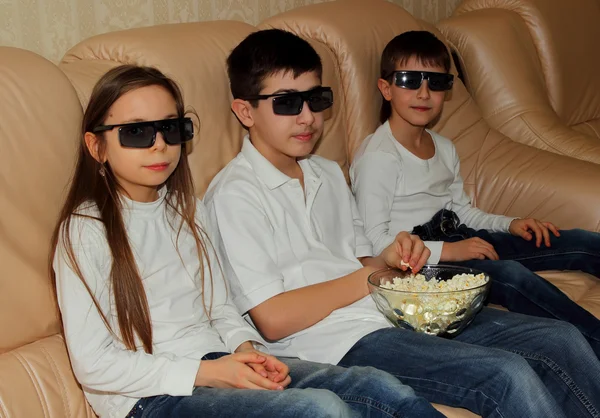 Дети едят попкорн и смотрят телевизор — стоковое фото