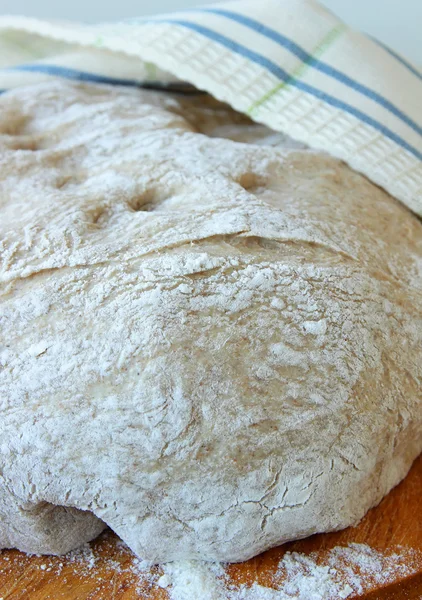 De afgewerkte deeg bedekt met een handdoek ligt op een schoolbord — Stockfoto