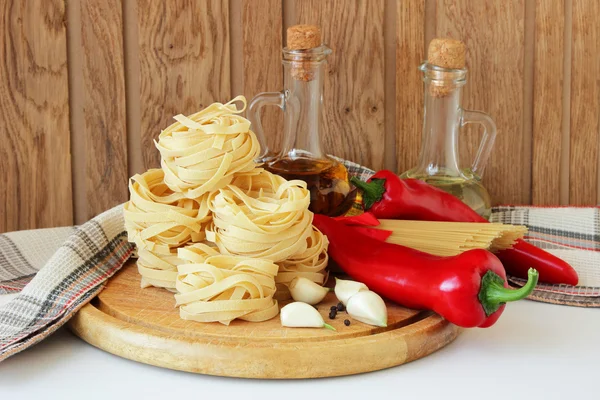 Massas alimentícias, pimentas, especiarias e garrafa de óleo — Fotografia de Stock