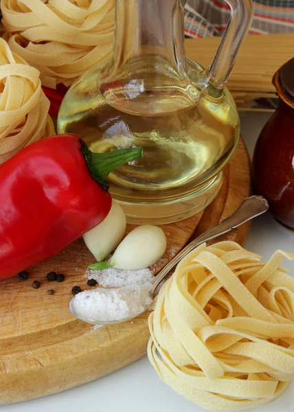 Massas alimentícias, pimentas, especiarias e garrafa de óleo — Fotografia de Stock