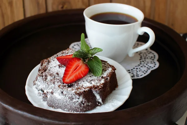 Plak van chocolade cake met aardbeien en bestrooid met poedersuiker — Stockfoto