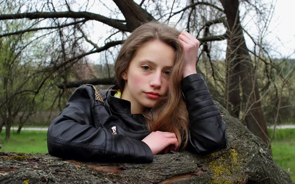 Hermosa chica apoyada en una rama de árbol — Foto de Stock