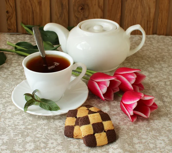 Taza de té negro, galletas y tulipanes — Foto de Stock