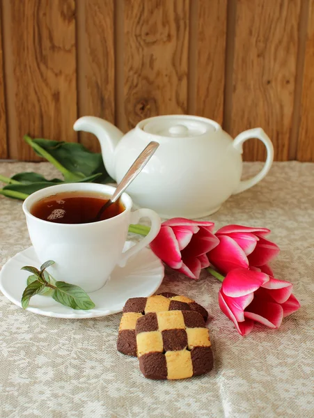 Čajový set, soubory cookie a tulipány — Stock fotografie