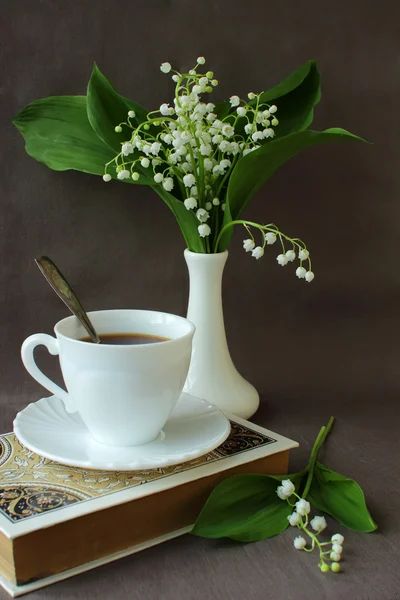 Maiglöckchen-Strauß, ein Buch und eine Tasse Kaffee — Stockfoto