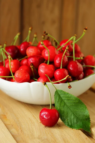 Ripe cherries in a bowl and one berry near her — Stock Photo, Image