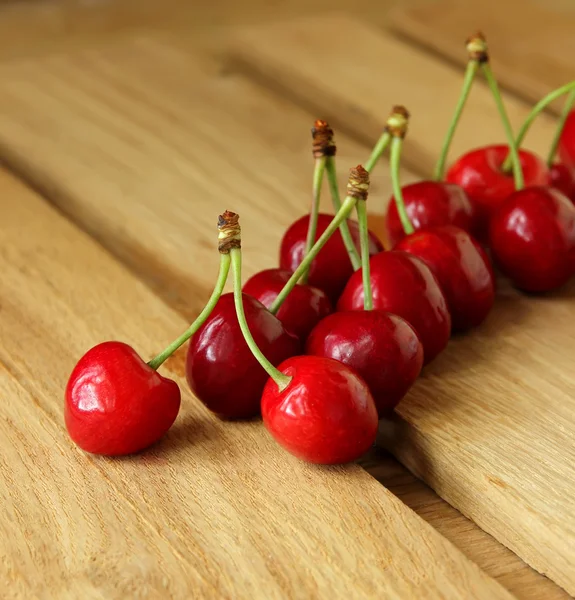 Ripe cherries lined in a row on a wooden table — Stock Photo, Image