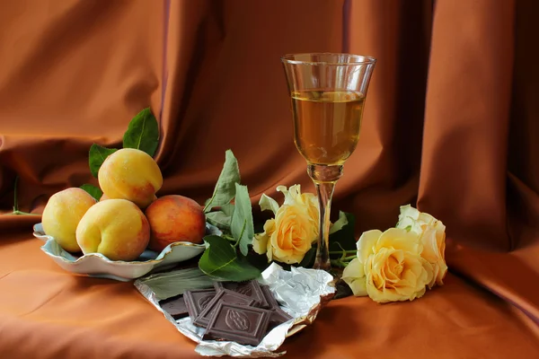 Glas vitt vin, persikor, rosor och chokladkaka — Stockfoto