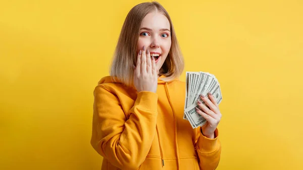 Boldog izgatott gazdag fiatal nő nyer pénzt készpénzt. Lady hold Dollar verem meglepett örül lottó győzelem elszigetelt sárga színű háttér. Hosszú web banner — Stock Fotó