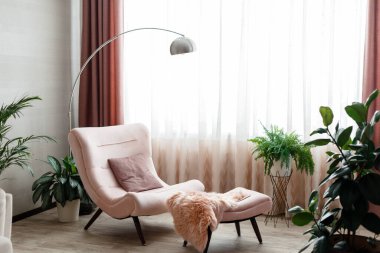 İçerisi şık, içi boş koltuğu pencere kenarına yakın, gri duvarda kimse yok. Evin içini rahatlatmak için rahat bir yer. Kanepede, çiçeklerin arasında yerli bitkilerin arasında. Pembe rahat koltuk