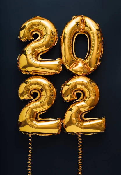 2022 anno palloncino testo in oro su sfondo nero con nastri d'oro. Felice anno nuovo invito vigilia con palloncini foglio d'oro di Natale 2022 carta regalo verticale — Foto Stock