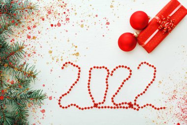 Madalyalı 2022 tebrik kartı. Noel kompozisyon kartın kutlu olsun. Beyaz tahta masanın üstünde hediye kutuları var. Kutlama kartı, 2022 harfli kırmızı çelenk. Düz yatıyordu