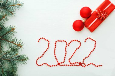 2022 'de yeni yıl kompozisyon kartında beyaz ahşap masada hediye kutuları var. Kutlama kartı 2022 numaralı kırmızı çelenk şeklinde. Düz yatıyordu